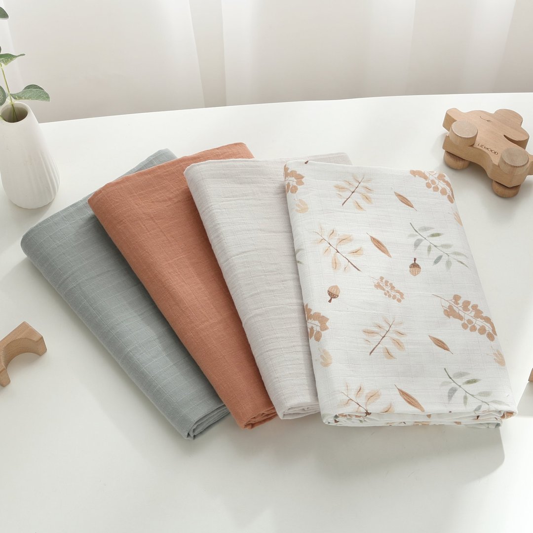 Four folded muslin blankets in earth tones